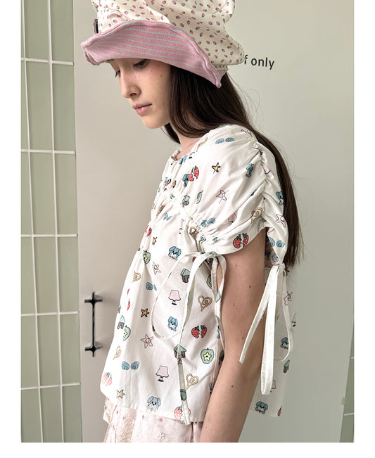 Unsocial Night short sleeve top showcasing a whimsical naive-art illustration print, central ruched detailing, and functional front ribbon ties