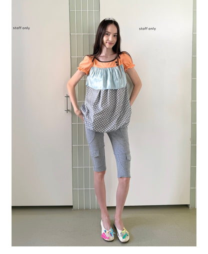 Unsocial Night short sleeve top showcasing a whimsical polka dot print, structured puff sleeves, contrast patchwork, and a voluminous bubble hem