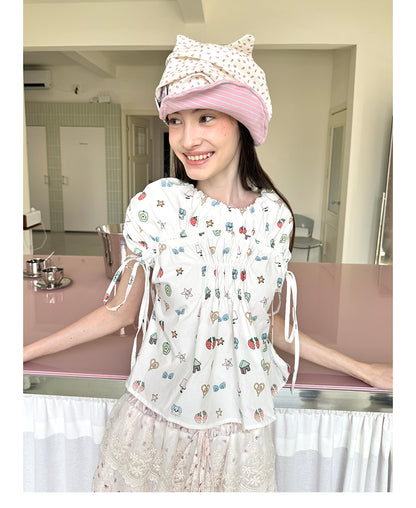 Unsocial Night short sleeve top showcasing a whimsical naive-art illustration print, central ruched detailing, and functional front ribbon ties