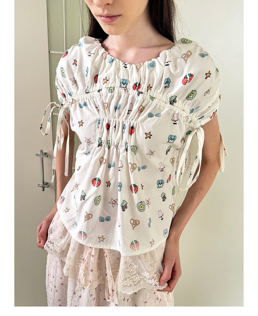 Unsocial Night short sleeve top showcasing a whimsical naive-art illustration print, central ruched detailing, and functional front ribbon ties