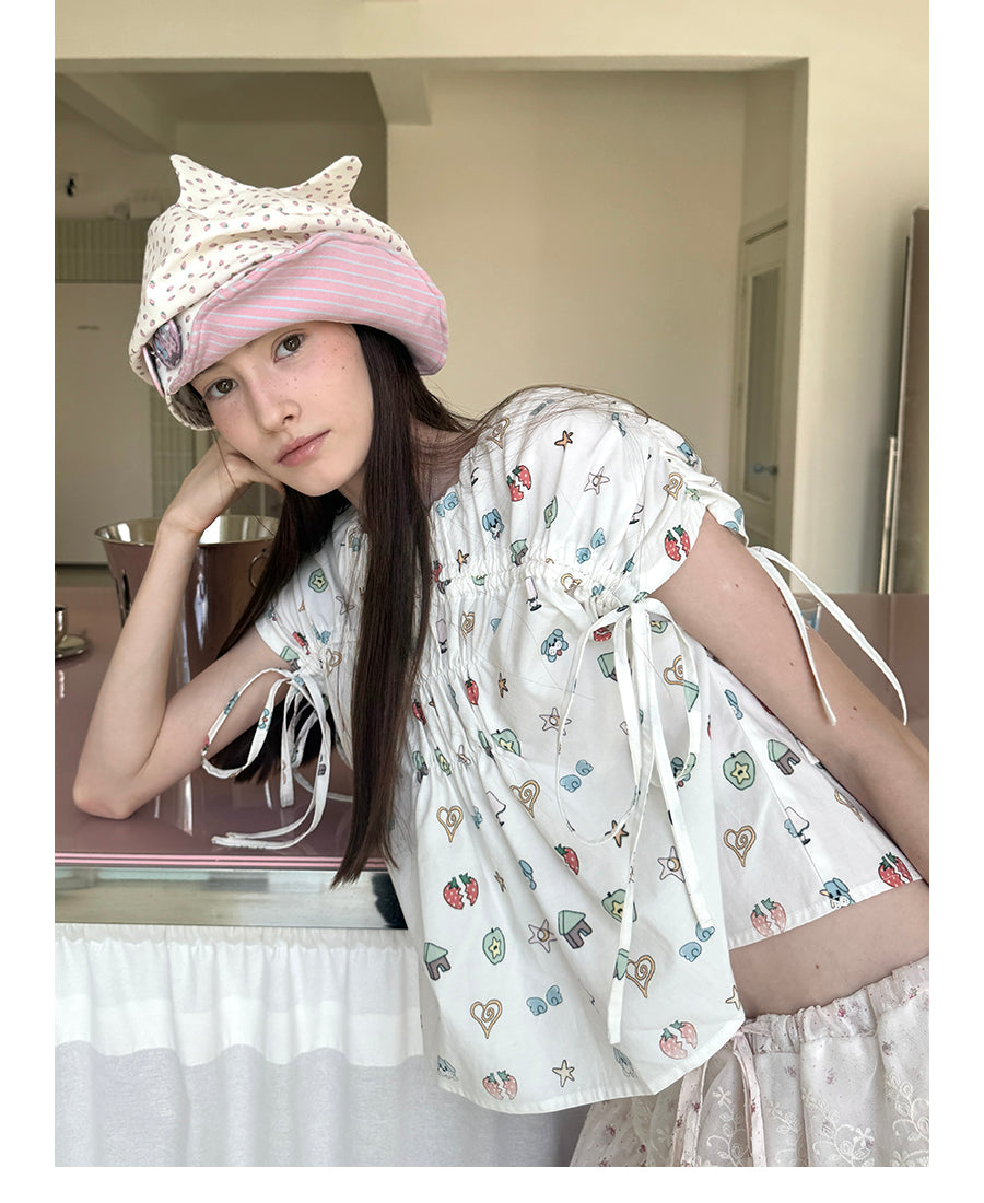 Unsocial Night short sleeve top showcasing a whimsical naive-art illustration print, central ruched detailing, and functional front ribbon ties