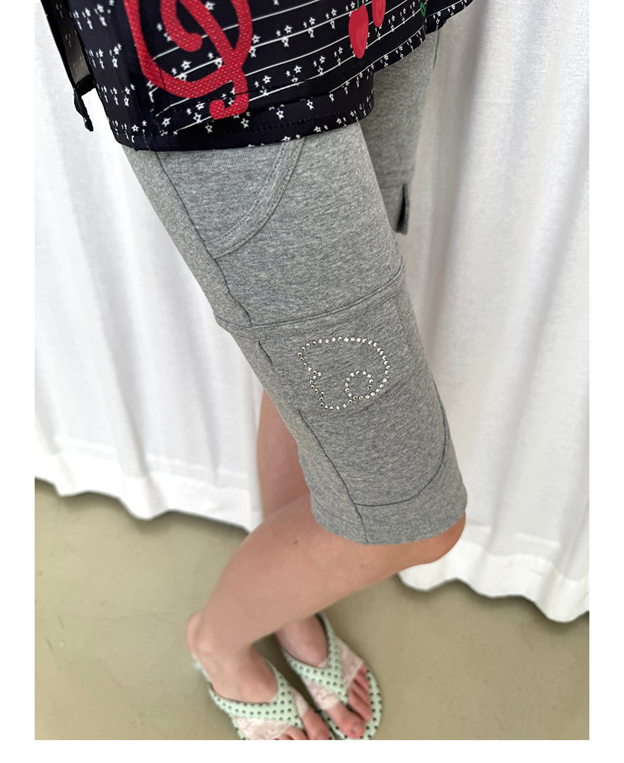 Unsocial Night fitted biker shorts showcasing the contrast patchwork seams, slim-fit technical fabric, and custom sparkling rhinestone details